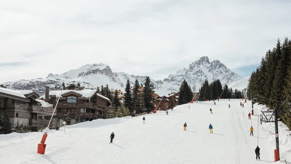 Skiers on the Bellecote piste passing Aman Le Melezin, Courchevel 1850