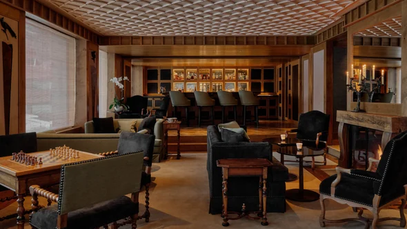 Armchairs, a chess table and a log fire in the Salon at Aman Le Melezin, Courchevel 1850