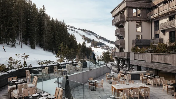 Timber tables on the Aman Le Melezin terrace above the Bellecote piste with Courchevel behind