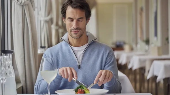 A guest at a table in the restaurant at Chenot Palace Weggis, with a vegetable dish on the plate