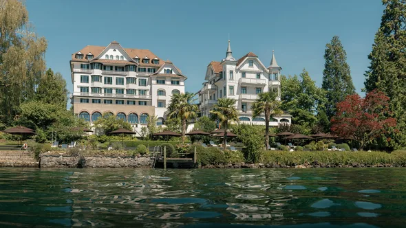 Chenot Palace Weggis on the shore of Lake Lucerne, seen from the water on a sunny day