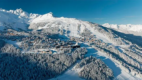 Courchevel 1850 seen from the air, its pistes running down between forested ridges