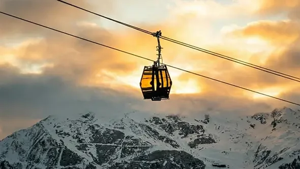 A Saulire Express gondola cabin crossing the valley at sunset in Les Trois Vallees