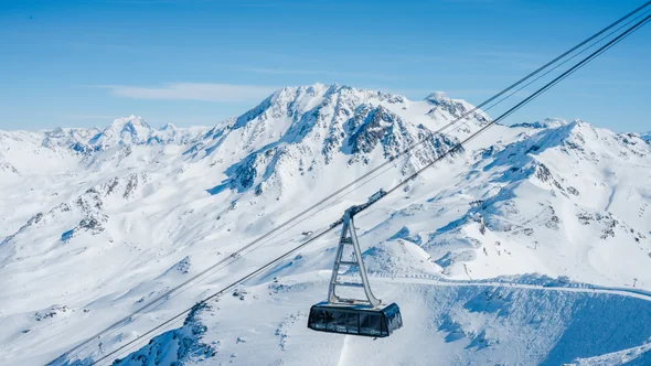 A Cime Caron cable car cabin on its way up over the peaks of Val Thorens