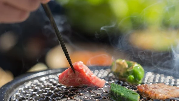 Wagyu being turned over glowing embers on a tableside grill at Aman Le Melezin, Courchevel 1850