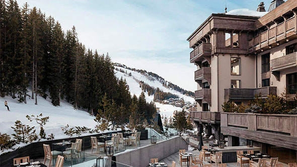 The sunny terrace of the Aman Le M&eacute;l&eacute;zin hotel overlooking the snowy slopes and coniferous forest of Courchevel. / Солнечная терраса отеля Aman Le M&eacute;l&eacute;zin с видом на заснеженные склоны и хвойный лес Куршевеля.