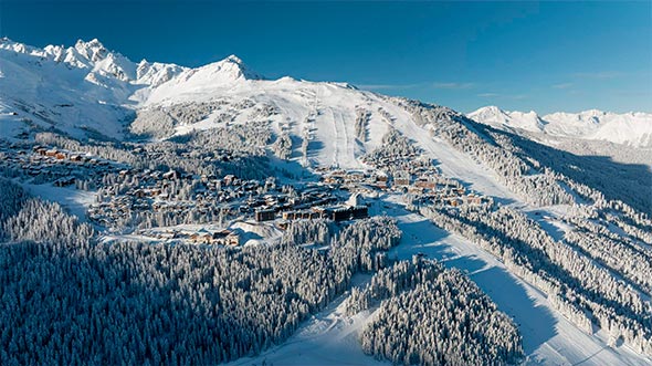 Aerial view of the snow-covered Courchevel 1850 village and ski slopes in the Les 3 Vall&eacute;es region. / Аэрофотосъемка заснеженной деревни Куршевель 1850 и горнолыжных склонов в регионе Три Долины.