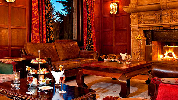 Cozy interior of Da Vittorio St. Moritz restaurant with a richly set table, candles, and a wall decorated with a large relief panel featuring figures.
