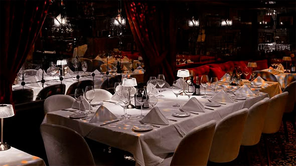 Luxury interior of Django restaurant and piano bar in Courchevel 1850 featuring elegantly set tables and a private club atmosphere. / Роскошный интерьер ресторана и пиано-бара Django в Куршевеле 1850 с сервированными столами и атмосферой закрытого клуба.