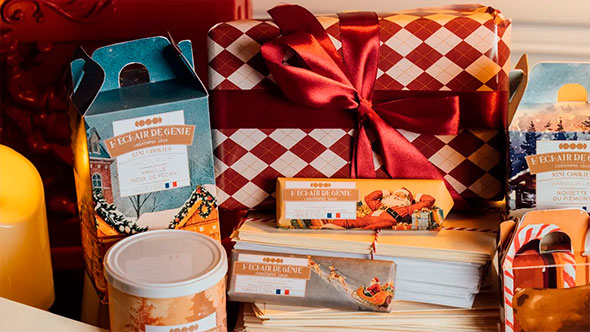 Close-up of festive Christmas desserts and chocolate bars by Christophe Adam (L’Éclair de Génie), packaged in themed boxes with bows, highlighting the high-end patisserie at Hôtel Barrière Les Neiges.