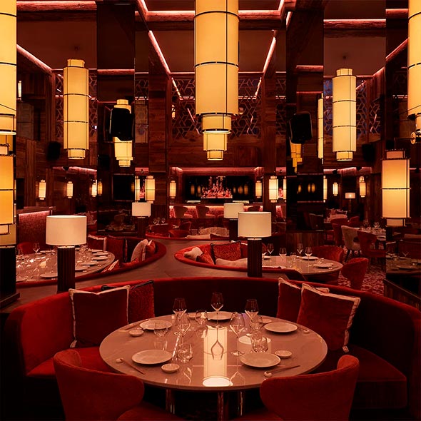 Interior of Kinugawa Courchevel 1850 restaurant featuring red velvet banquettes, wood paneling, and distinctive cylindrical lantern lighting fixtures.