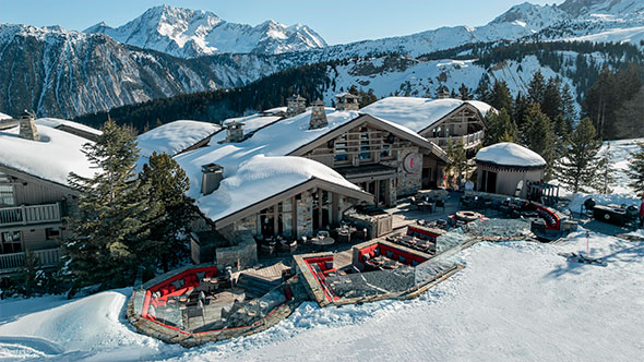 General view of the luxurious Le K2 Altitude chalet complex, situated directly on a snowy slope, featuring a panoramic terrace and mountain views.
