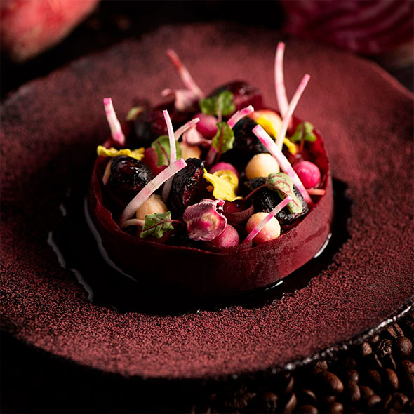 Elegant appetizer at the Altiplano restaurant: a dish based on beetroot and berries, served on a dark plate with red accents and delicate sprouts.