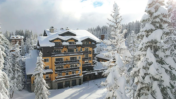 Exterior of the five-star historic hotel Mont Blanc Chamonix, surrounded by snow-covered pines in the heart of Chamonix