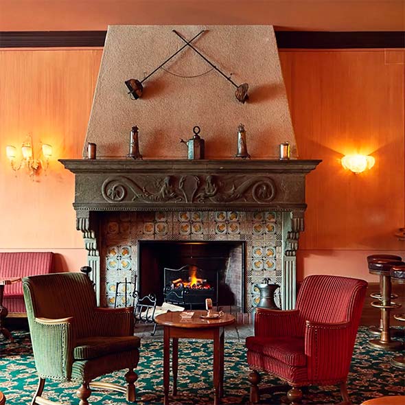Cozy interior of Renaissance Bar with a richly set table, candles, and a wall decorated with a large relief panel featuring figures.