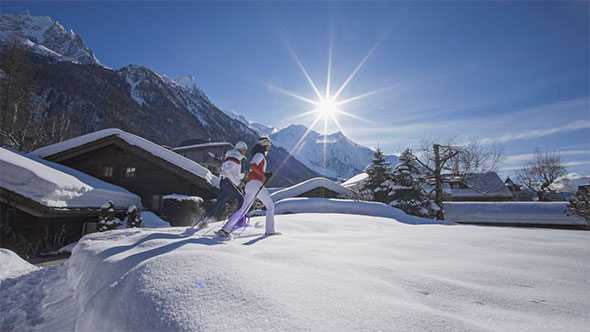 Skiers against the backdrop of snow-covered chalets and mountain panorama on a sunny day in Chamonix