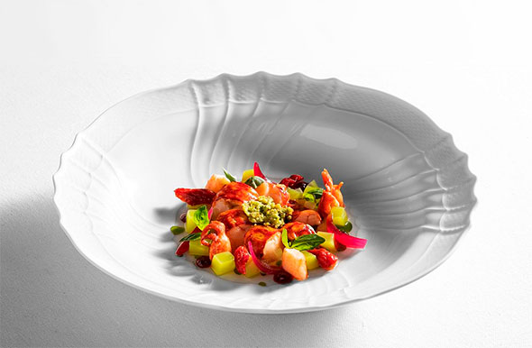 Exquisite dish featuring shrimp, fruits, and greens, served in a deep white bowl.