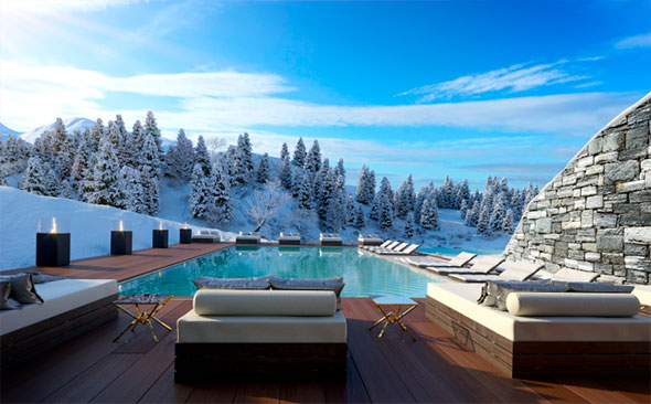 An outdoor heated pool at Ultima Hotel Gstaad with a dark wooden deck and luxury daybeds, surrounded by snow-covered fir trees under a bright blue sky, showcasing a winter wellness retreat.