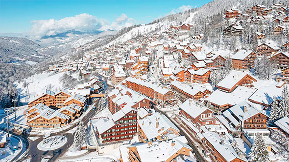 Aerial view of the snow-covered alpine village of Méribel (French Alps), showing tightly clustered chalets and premium residences surrounded by mountain slopes, ideal for a winter ski holiday.