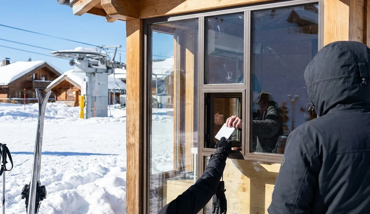 Collecting a lift pass at a ticket window on the snow front