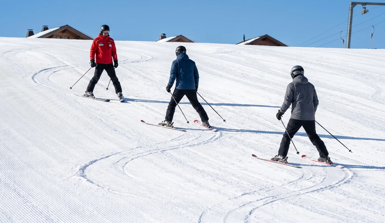 Instructor showing the snowplough to two adult pupils on a nursery slope