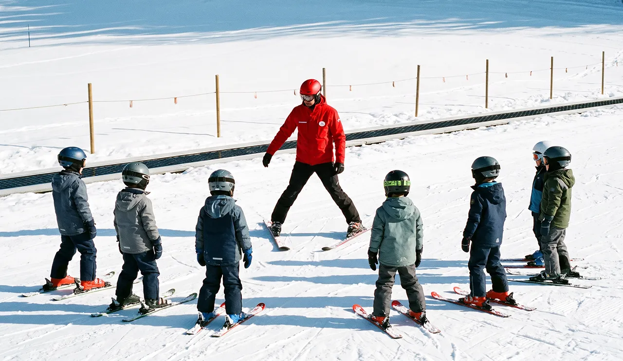 ESF instructor teaching a group of children in helmets on a nursery slope