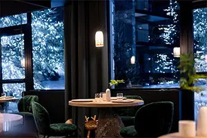 Cozy evening interior of Alpage restaurant in Courchevel with a view of illuminated trees