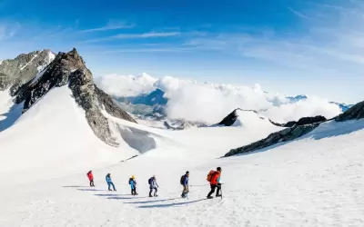 A group of mountaineers walking roped up on a glacier with a guide