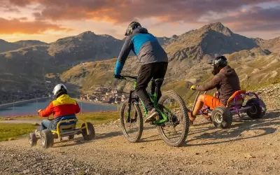 People descending on karts and a mountain bike down a slope in Val Thorens.