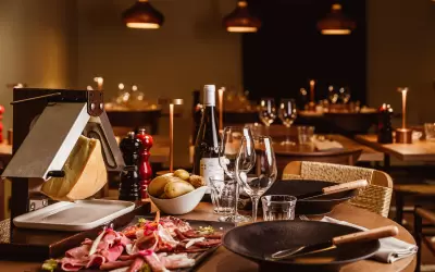 Traditional raclette cheese dish and cold cuts on a table at La Laiterie restaurant