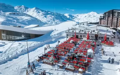 Sunny terrace of La Maison restaurant in Val Thorens among snowy mountains.
