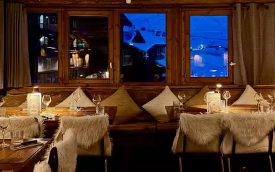 Cosy wooden interior of Le Chaudron Magique restaurant with a mountain view.
