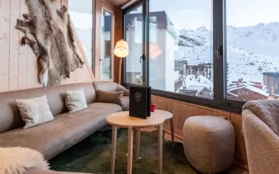 Cosy lounge area of Le Confidentiel restaurant with a sofa and panoramic mountain views