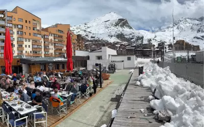 Outdoor terrace of Le Rooftop restaurant with guests against snowy mountains