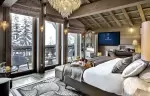 Bedroom with a crystal chandelier, beamed ceiling and balcony doors at Lys Martagon, Courchevel 1850