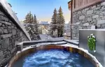 Wooden outdoor hot tub on a snowy terrace facing fir trees at Lys Martagon, Courchevel 1850