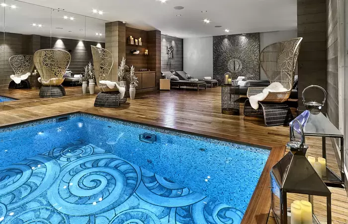 Pool and relaxation area with wicker armchairs in the Lys Martagon spa, Courchevel 1850