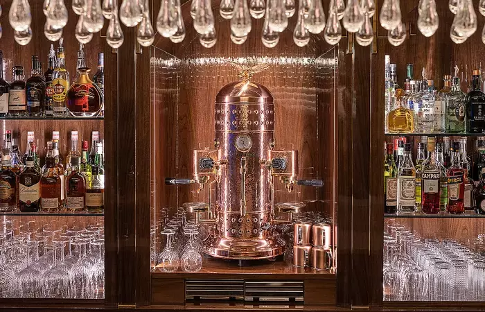 Back bar with spirits, glassware and a copper centrepiece under hanging crystals, Lys Martagon