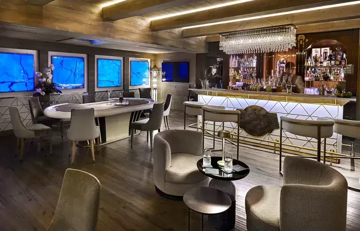 Prohibition Bar with a large oval table, armchairs and a backlit counter at Lys Martagon, Courchevel 1850