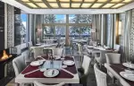 Restaurant with panoramic windows onto snowy fir trees and a fireplace, Lys Martagon, Courchevel 1850