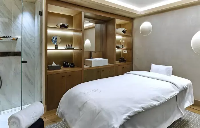 Treatment room with a massage table and wooden shelving in the Lys Martagon spa