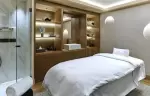 Treatment room with a massage table and wooden shelving in the Lys Martagon spa