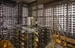 Wine cellar with illuminated bottle racks and a glass table at Lys Martagon, Courchevel 1850