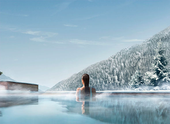 Woman relaxing in a heated outdoor infinity pool at a luxury SPA (Lefay Dolomites), overlooking a snow-covered mountain landscape.
