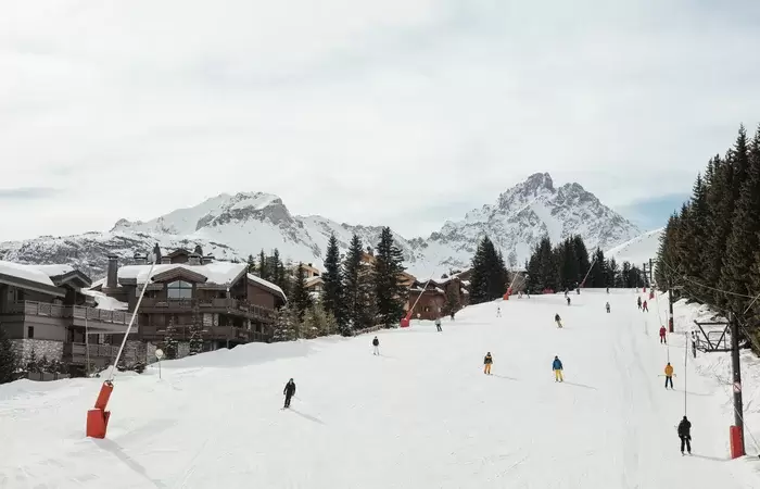 Skiers on the Bellecote piste passing Aman Le Melezin, Courchevel 1850