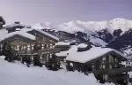 Snow-covered chalet roofs at dusk with the Courchevel peaks behind