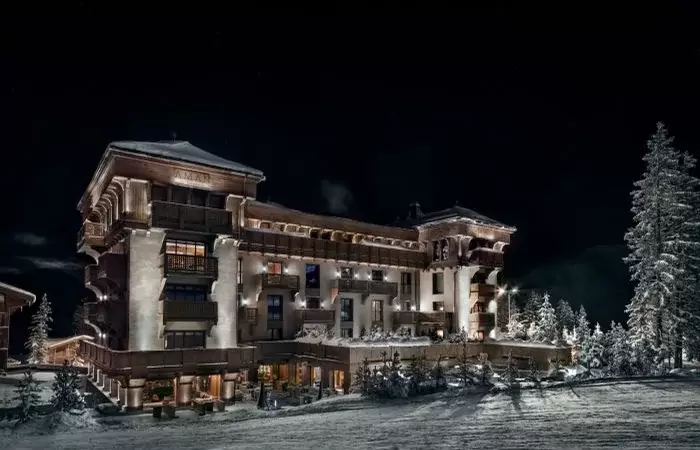 The hotel lit from within at night, snow banked against its terraces