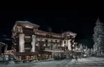 The hotel lit from within at night, snow banked against its terraces