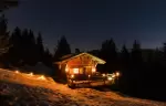 Lit mountain chalet at Les Pres de la Croix under a starry sky