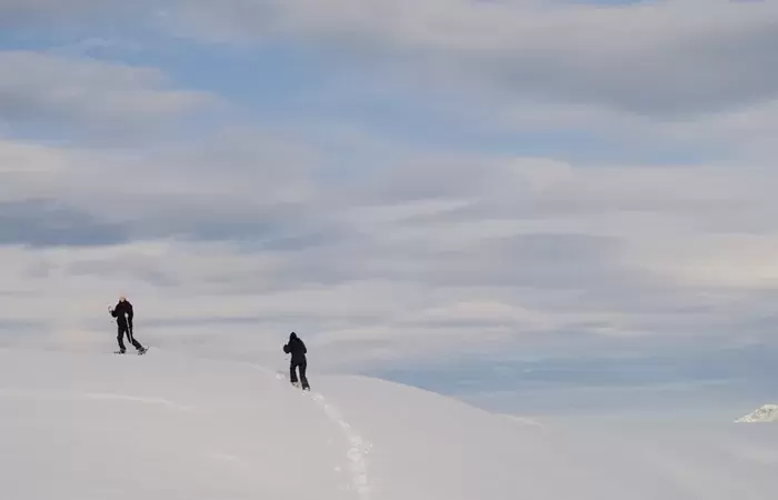 Two ski tourers climbing a wide untracked slope above Courchevel